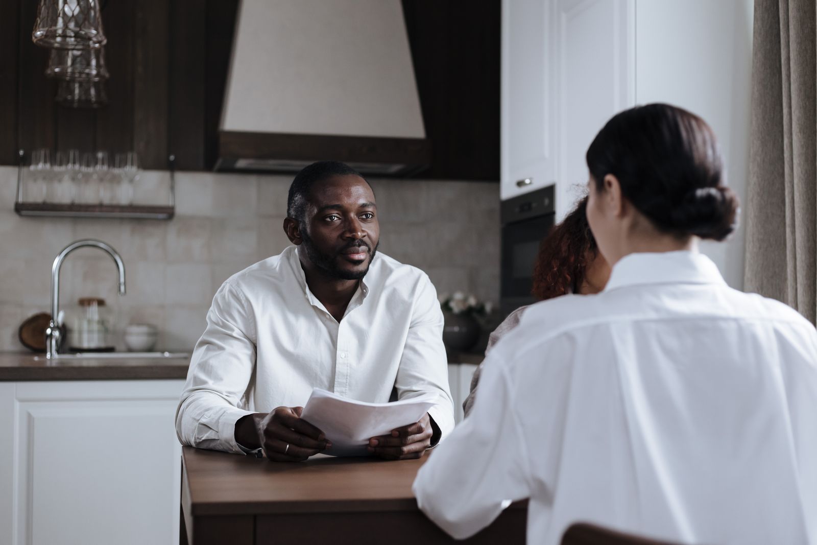 Homebuyer Report FAQs London — Young couple in an Essex kitchen reviewing their homebuyer report with a surveyo