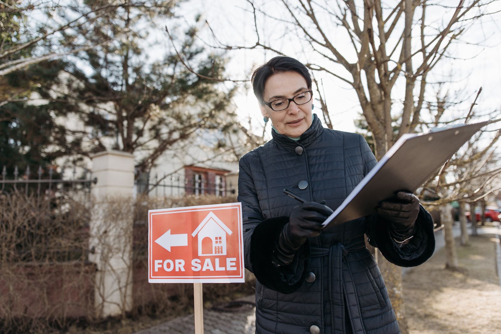 Surveyor Fees In The Home Counties — A surveyor in Essex inspects the exterior wall of a family house, taking notes a Surveyor Fees In The Home Counties — A surveyor in Essex inspects the exterior wall of a family house, taking notes a
